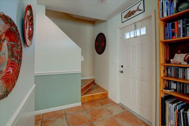 entryway with light tile patterned flooring and a textured ceiling