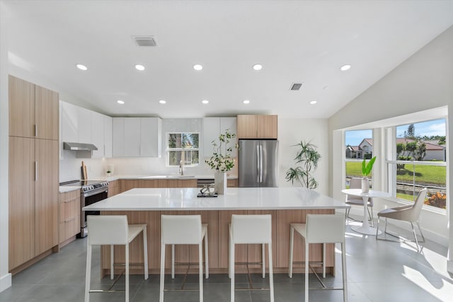 kitchen featuring a kitchen island, modern cabinets, appliances with stainless steel finishes, light countertops, and white cabinetry