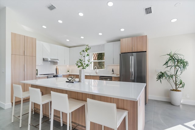 kitchen featuring white cabinets, a kitchen island, a kitchen bar, and stainless steel appliances