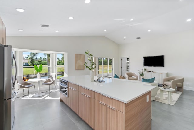 kitchen featuring a wealth of natural light, a kitchen island, vaulted ceiling, and appliances with stainless steel finishes