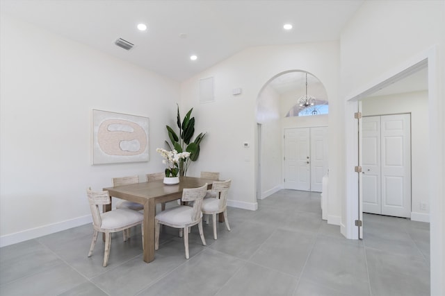 dining area with high vaulted ceiling, light tile patterned flooring, and a notable chandelier