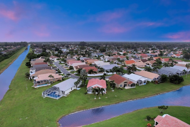 aerial view at dusk with a residential view and a water view