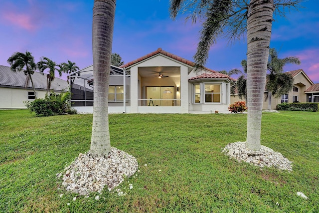 view of front of home with a yard, ceiling fan, and a lanai