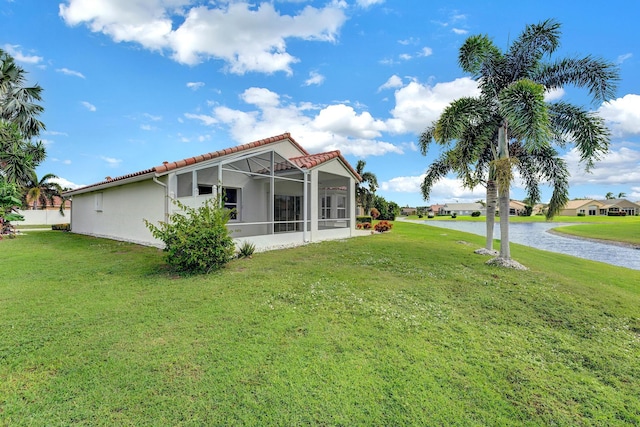 back of property featuring a yard, a water view, and glass enclosure