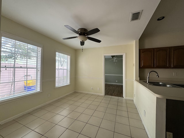 unfurnished dining area featuring ceiling fan, sink, and light tile patterned floors