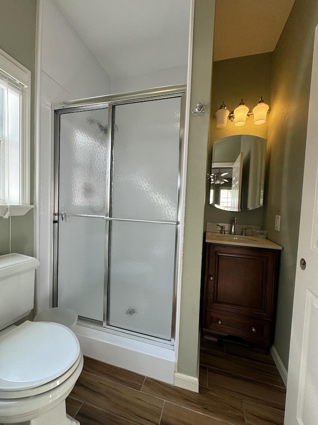 bathroom featuring vanity, ceiling fan, toilet, and a shower with door