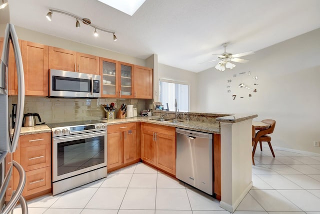 kitchen with light stone countertops, ceiling fan, kitchen peninsula, light tile patterned floors, and appliances with stainless steel finishes