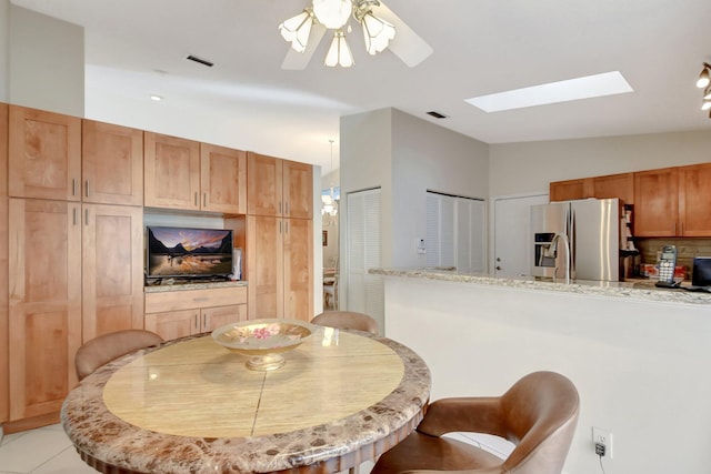 tiled dining room featuring ceiling fan and lofted ceiling with skylight