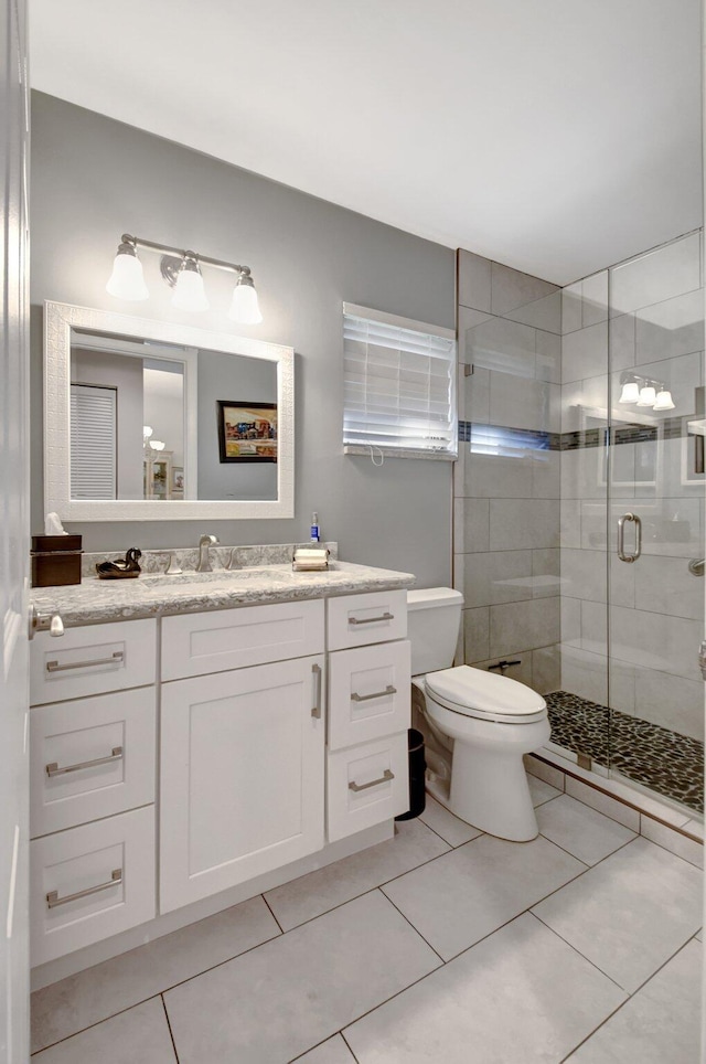 bathroom featuring tile patterned floors, vanity, toilet, and an enclosed shower