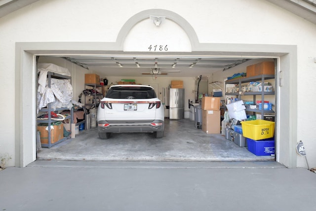 garage with stainless steel fridge and a garage door opener