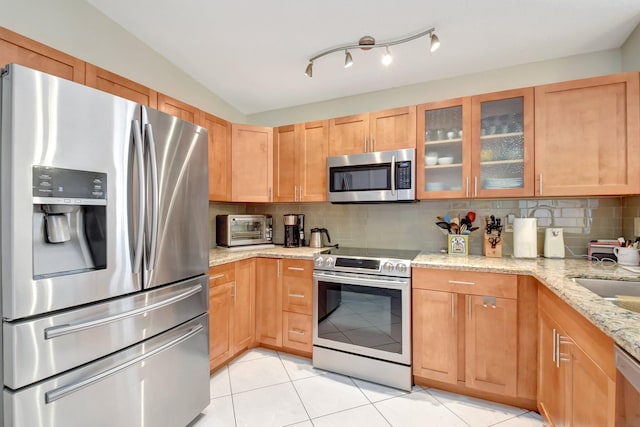 kitchen featuring light tile patterned floors, backsplash, stainless steel appliances, and light stone counters