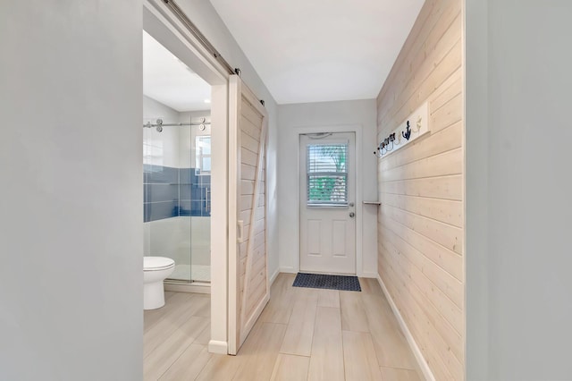 doorway to outside featuring a barn door and wooden walls