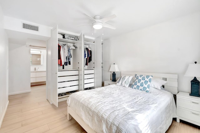 bedroom with ceiling fan, a closet, ensuite bathroom, and light hardwood / wood-style flooring