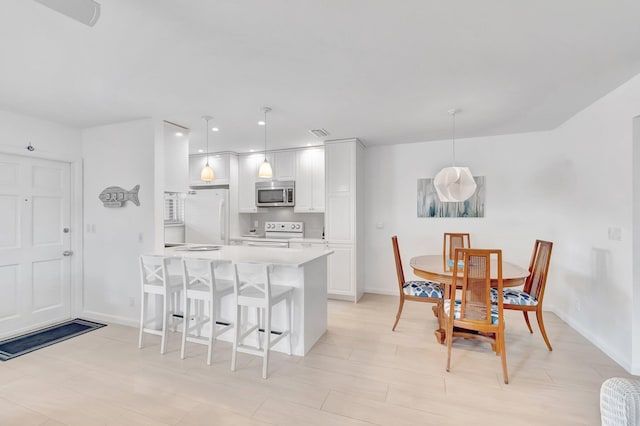 kitchen featuring white cabinetry, hanging light fixtures, and white appliances