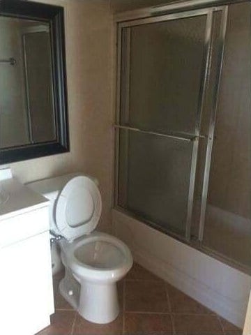 full bathroom with tile patterned flooring, vanity, toilet, and combined bath / shower with glass door