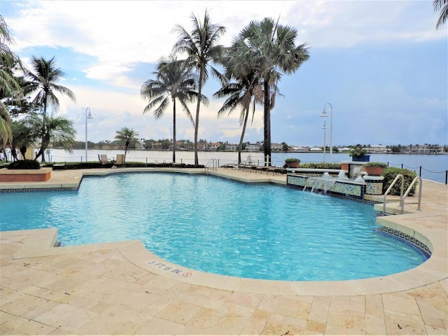 view of pool with pool water feature, a water view, and a patio area