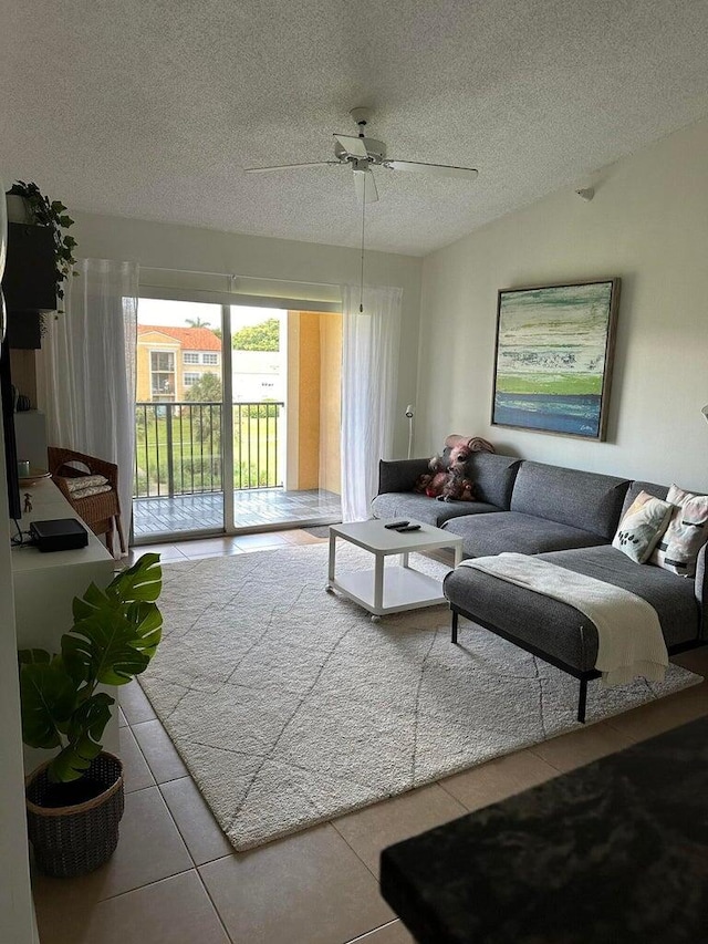 living room featuring ceiling fan, light tile patterned floors, and a textured ceiling