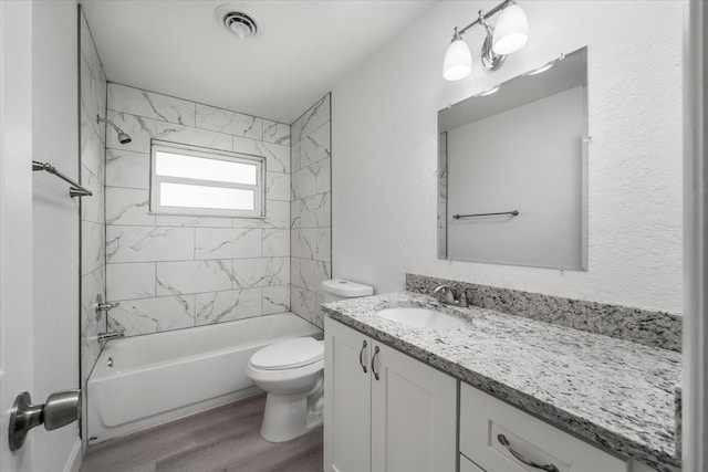 full bathroom featuring hardwood / wood-style floors, vanity, toilet, and tiled shower / bath