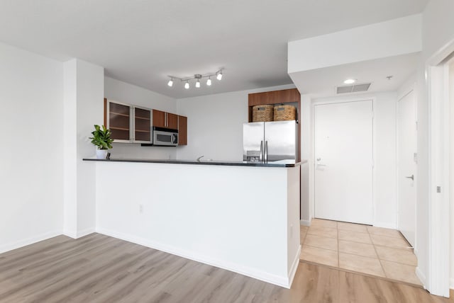 kitchen with kitchen peninsula, appliances with stainless steel finishes, and light hardwood / wood-style floors