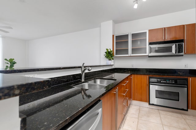 kitchen featuring dark stone countertops, sink, light tile patterned flooring, and stainless steel appliances