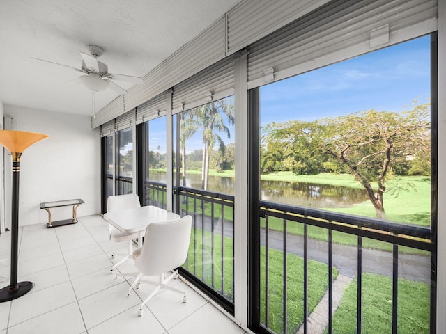 unfurnished sunroom featuring ceiling fan and a water view