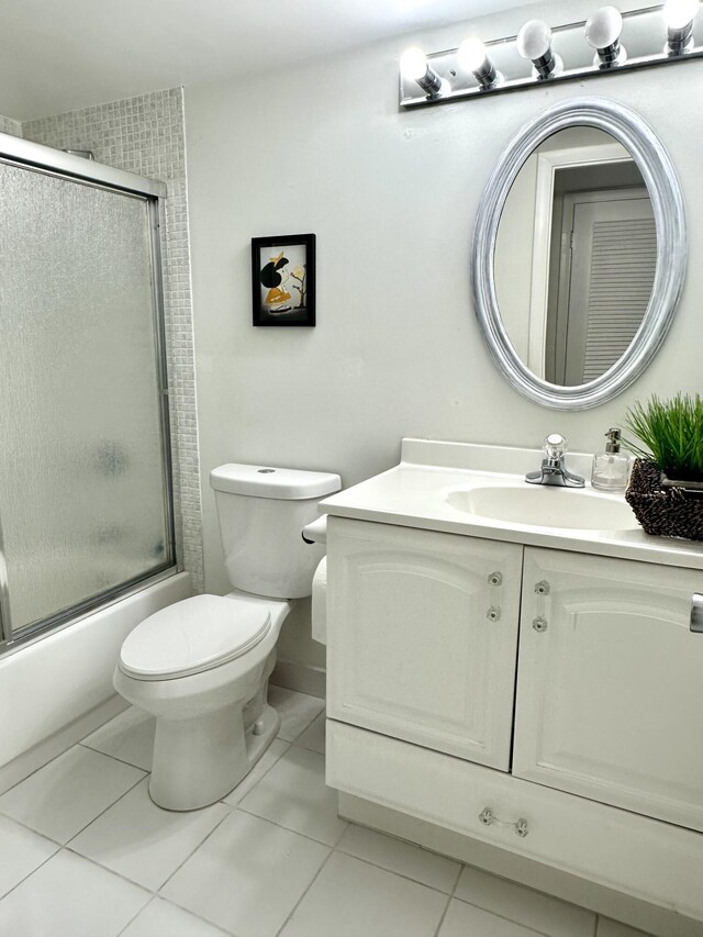 full bathroom featuring tile patterned flooring, vanity, toilet, and combined bath / shower with glass door