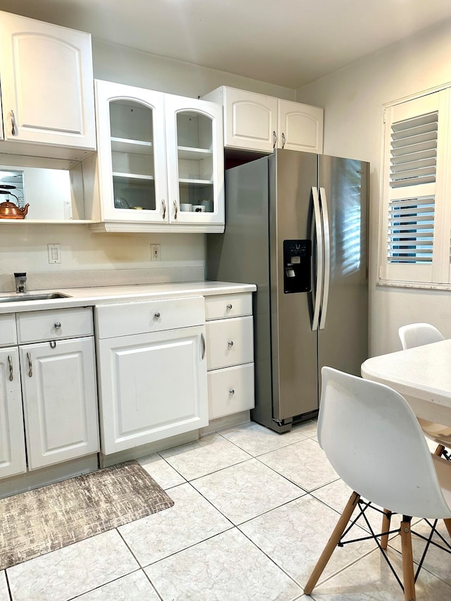 kitchen featuring light tile patterned floors, white cabinets, and stainless steel refrigerator with ice dispenser