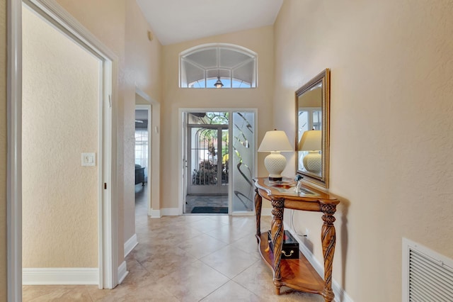 entrance foyer with light tile patterned flooring and high vaulted ceiling