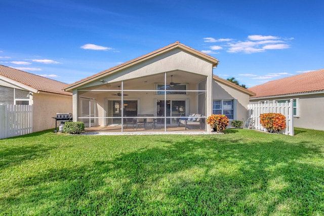 rear view of property featuring a yard, ceiling fan, and a sunroom