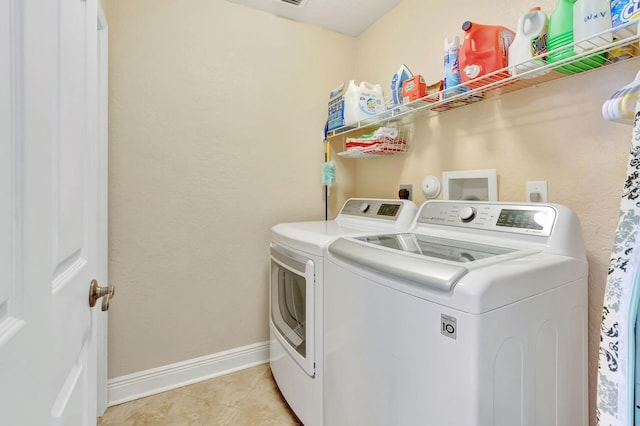 clothes washing area with light tile patterned floors and washing machine and clothes dryer