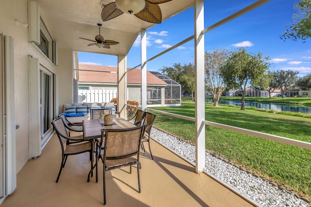 sunroom with ceiling fan and a water view