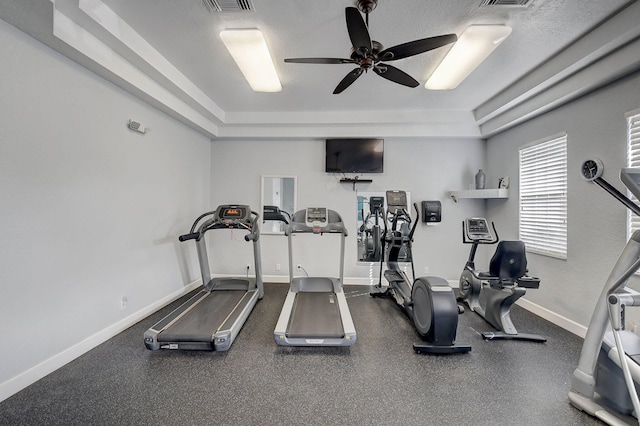 exercise area featuring ceiling fan and a tray ceiling