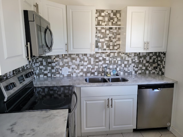 kitchen featuring white cabinets, decorative backsplash, stainless steel appliances, and sink