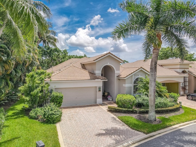 mediterranean / spanish-style house featuring a garage and a front yard