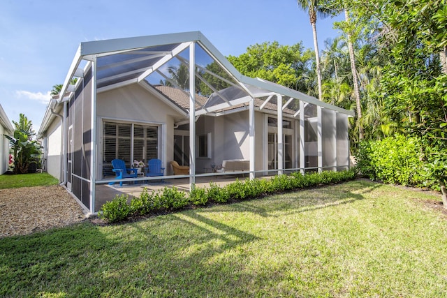 rear view of house with glass enclosure, a yard, and a patio area