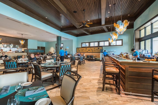 dining area featuring ceiling fan, beamed ceiling, a high ceiling, and wooden ceiling