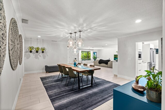 dining space with ornamental molding, a textured ceiling, and light hardwood / wood-style flooring