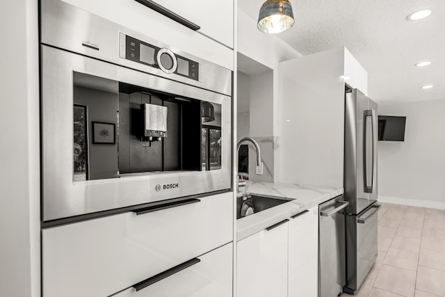 kitchen featuring light stone countertops, sink, light tile patterned floors, white cabinets, and appliances with stainless steel finishes