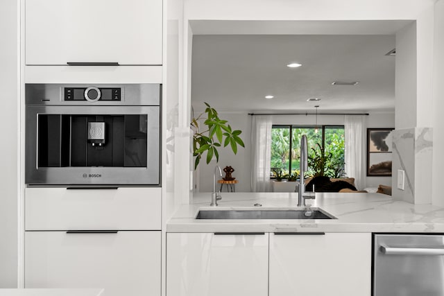 kitchen with light stone counters, sink, white cabinets, and appliances with stainless steel finishes