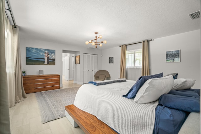 bedroom featuring light tile patterned floors, a textured ceiling, a closet, and a notable chandelier