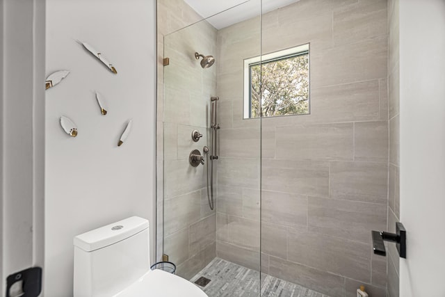 bathroom with a tile shower and toilet