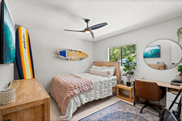 tiled bedroom with ceiling fan and a textured ceiling