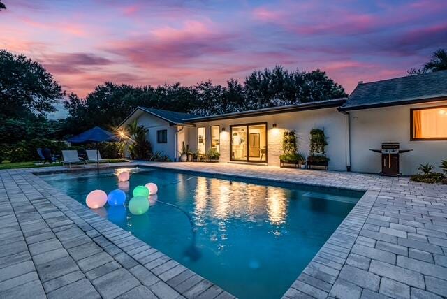 pool at dusk featuring a patio