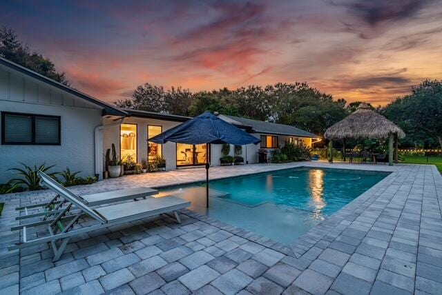 pool at dusk with a gazebo and a patio