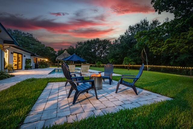 patio terrace at dusk with a yard and an outdoor fire pit