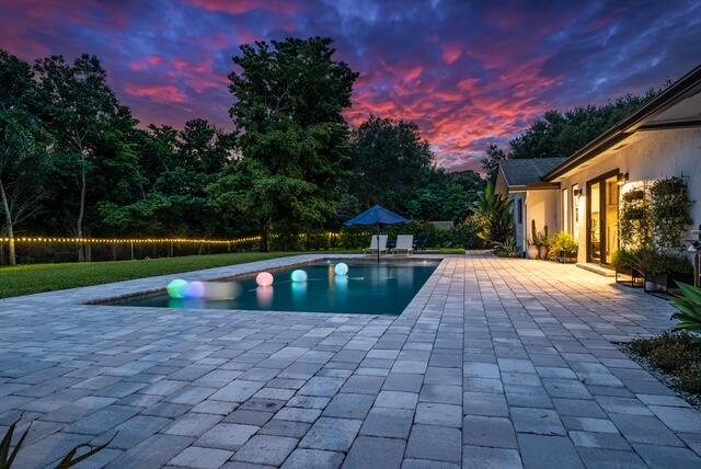 pool at dusk with a patio