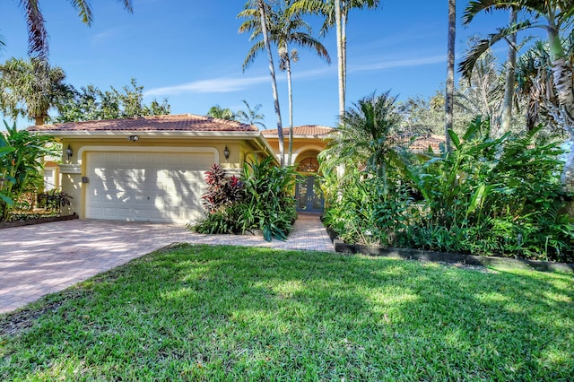 mediterranean / spanish home featuring a garage and a front lawn