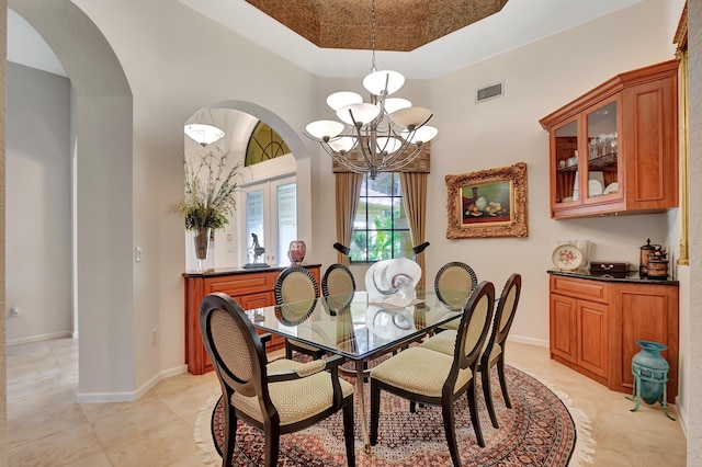 dining room with a notable chandelier, light tile patterned floors, and a tray ceiling