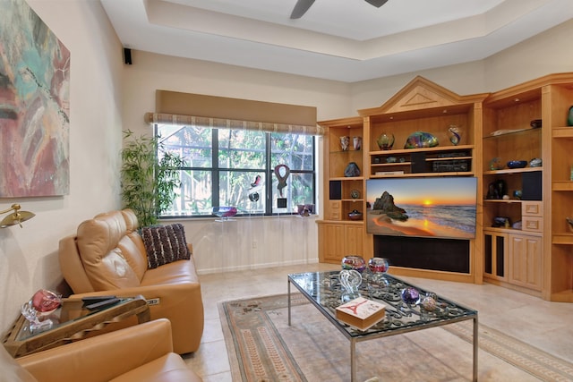 tiled living room with a raised ceiling and ceiling fan