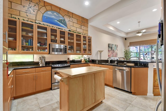 kitchen with ceiling fan, a kitchen island, sink, and appliances with stainless steel finishes